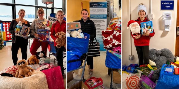 Volunteers with donated toys and games in a hospital play area.