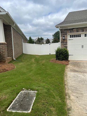 A neat side yard with green grass between two houses and a white fence.