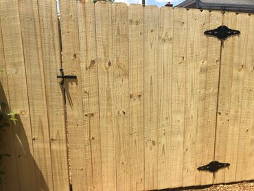 New wooden fence gate with black hardware and latch.