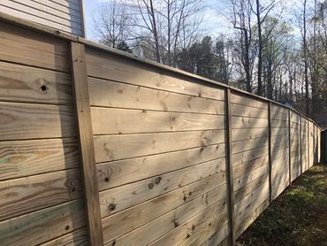 Long wooden fence along a backyard on a sunny day.