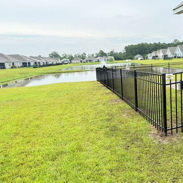 Residential area with a pond and black metal fence.