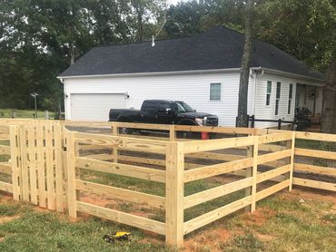 Newly built wooden fence around a grassy yard beside a house.