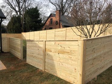 Newly installed wooden privacy fences around a yard with trees.