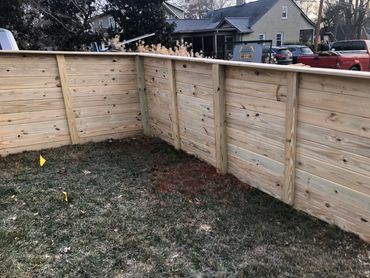 Newly installed wooden fence panels enclosing a backyard corner.
