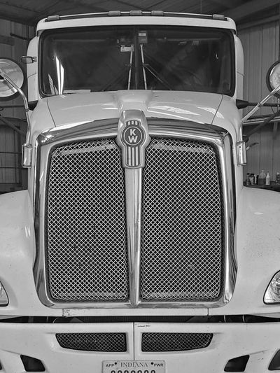 Front view of a Kenworth truck with a prominent grille and mirrors.