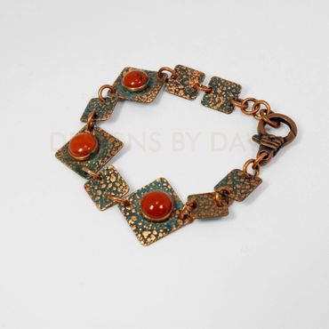 This square textured copper bracelet has an ammonia patina finish accented with red jasper.