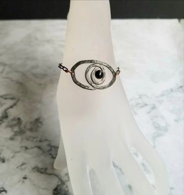 The is a hammered copper patina wire bracelet with a black onyx center.