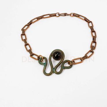 This folded copper wire bracelet has an ammonia patina finish with a black onyx accent.