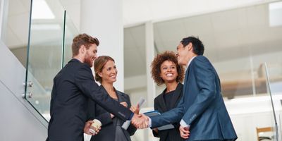 Male virtual CIO shaking smiling CEO hands while female VP and female director observe and smile
