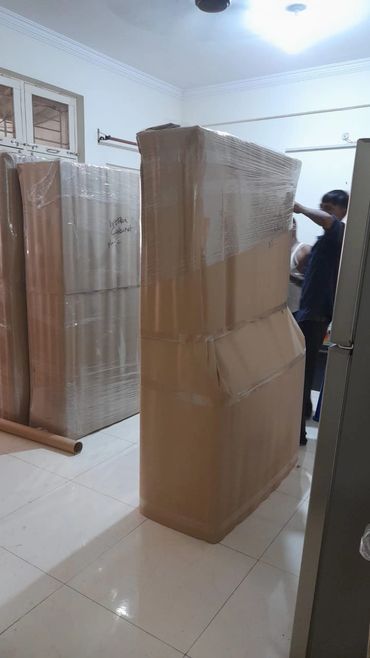 Large furniture pieces wrapped in protective material inside a room.