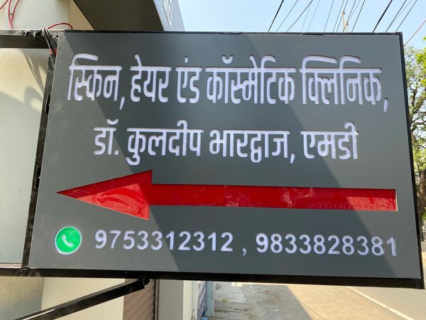 Clinic signboard with contact details and direction arrow.