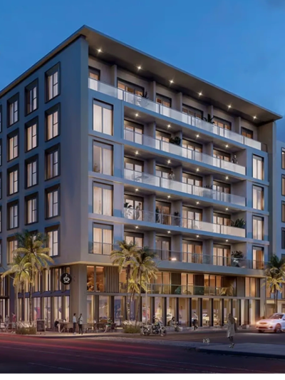 Modern apartment complex with balconies and street-level shops at dusk.