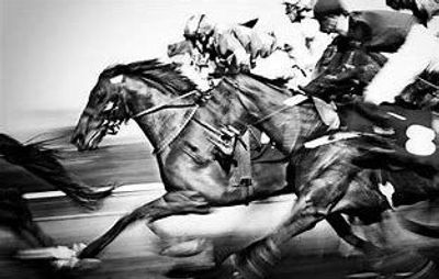 Black and white image of horses racing with jockeys.