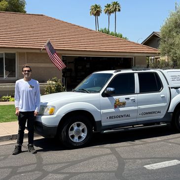 Man standing next to a white pest control truck in a suburban neighborhood.