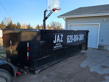Large black dumpster near a garage.