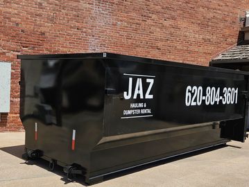 Black dumpster with Jaz Hauling & Dumpster Rental signage.