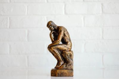 Estatua sentado en forma de estar pensando sobre una roca