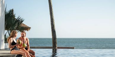 Couple enjoying fresh coconuts by the pool with ocean view.
