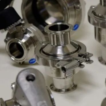 Various stainless steel sanitary fittings and clamps arranged on a surface.