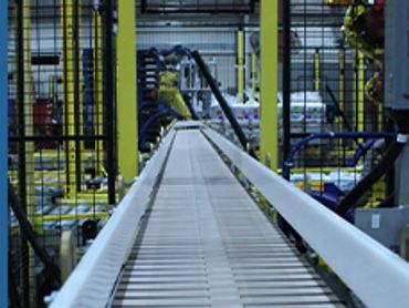 Automated conveyor belt system inside a factory with robotic arms.