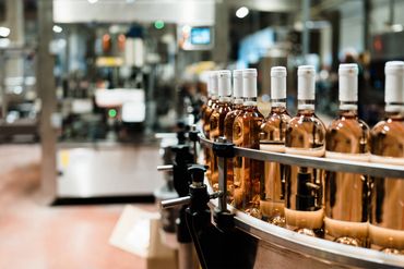 Bottles of rosé wine on a bottling line in a winery.