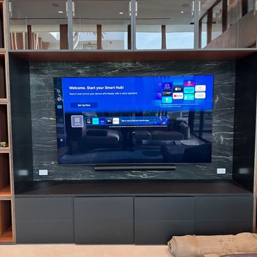 Modern living room with a large smart TV and sleek black entertainment unit.