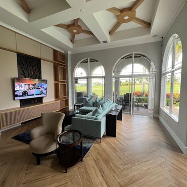 Spacious living room with vaulted ceiling, wood flooring, and large arched windows.