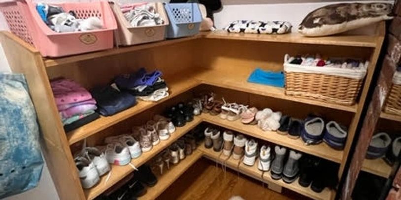 A child's closet that has been straightened up with shoes neatly paired and accessories in baskets.