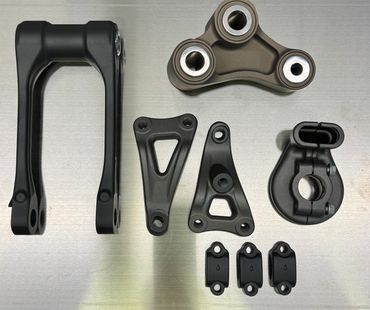 Various black mechanical parts arranged on a metallic surface.