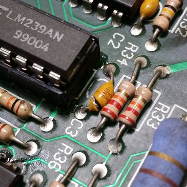 Broken Capacitor on a circuit board next to an IC socketed chip