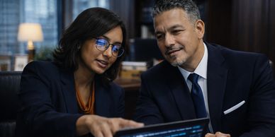 Two professionals discussing data on a tablet in an office.