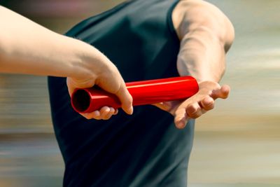 Runner passing a red baton in a relay race.