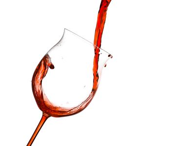 Red wine being poured into a tilted wine glass.