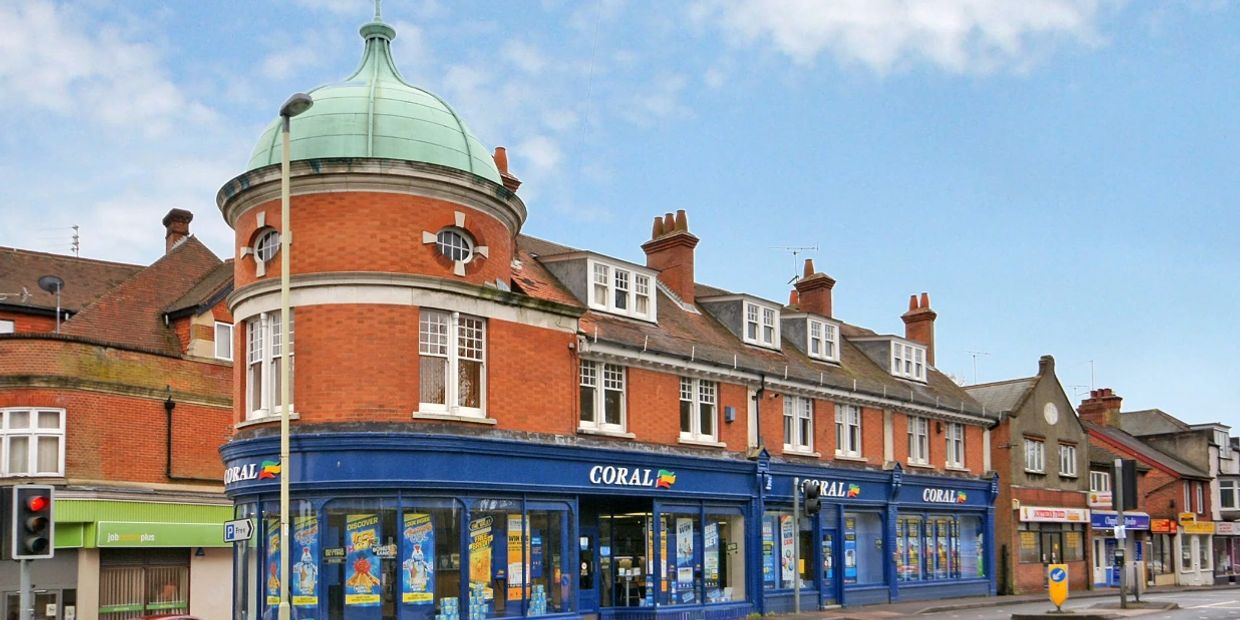 Traditional brick building with blue Coral storefront under a clear sky.