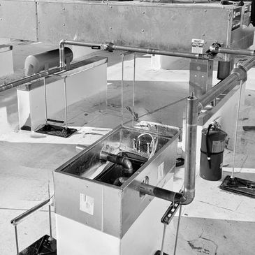 Industrial piping system connected to a metal tank on a rooftop.