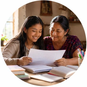 A grandmother and granddaughter smiling while reading a paper together.