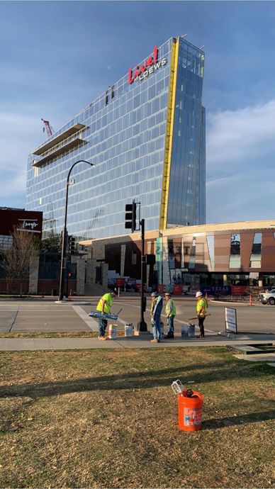 Workers on a sidewalk near a modern glass building.