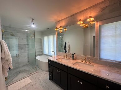 Modern bathroom with glass shower and dual sinks.