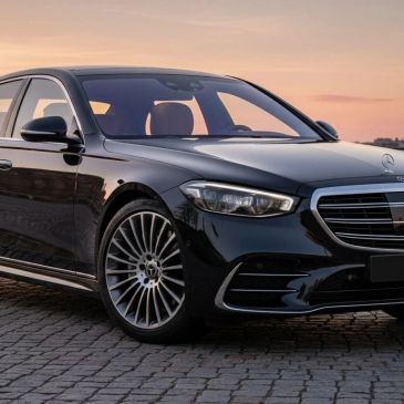 A sleek black Mercedes-Benz sedan parked on cobblestone at sunset.