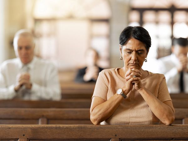 Woman praying in church pew.