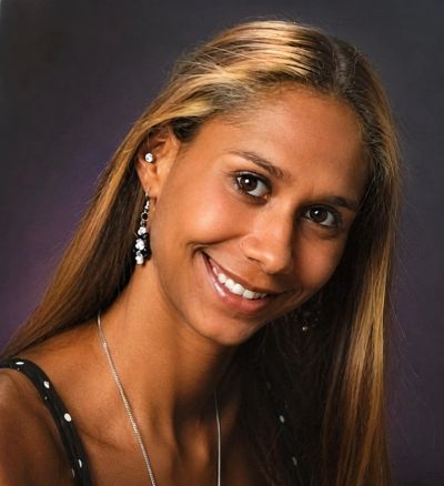 Smiling woman with long hair and dangling earrings.