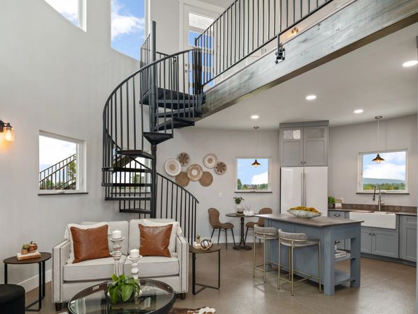 Modern living space with spiral staircase and open kitchen area.