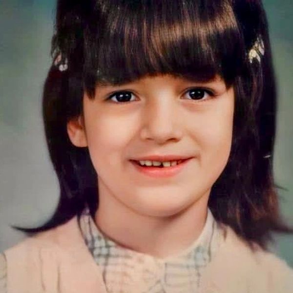 Young girl with dark hair smiling.