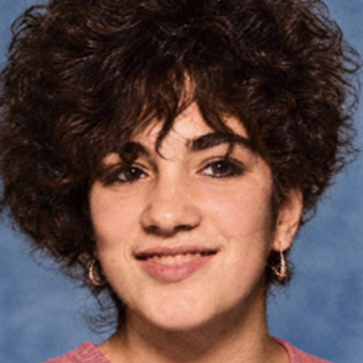 Smiling person with curly hair and earrings.