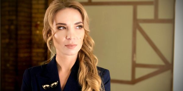 Confident woman with long blonde hair in a dark blazer looking to the side.