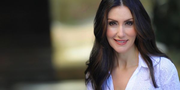 Smiling woman with long dark hair in a white blouse.