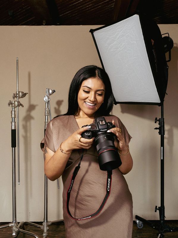 Woman smiling while holding a Canon camera in a studio.