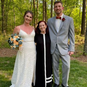 Bride, groom, and guest posing outdoors.