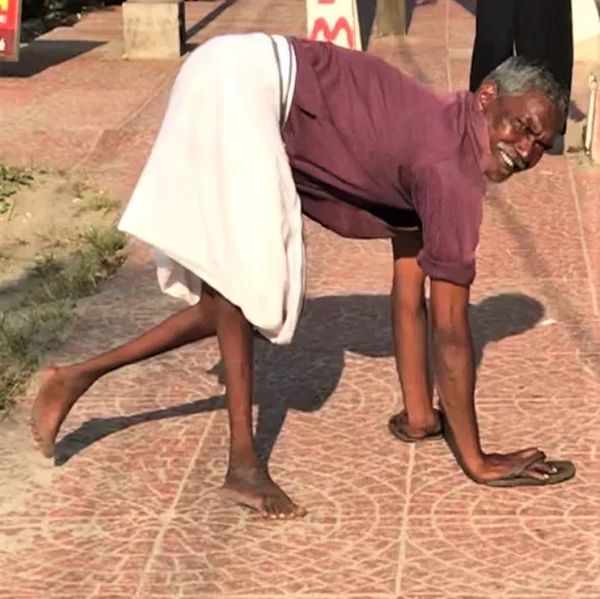 Vinju on a pavement in Kovalam, walking on all fours with flip-flops on his hands