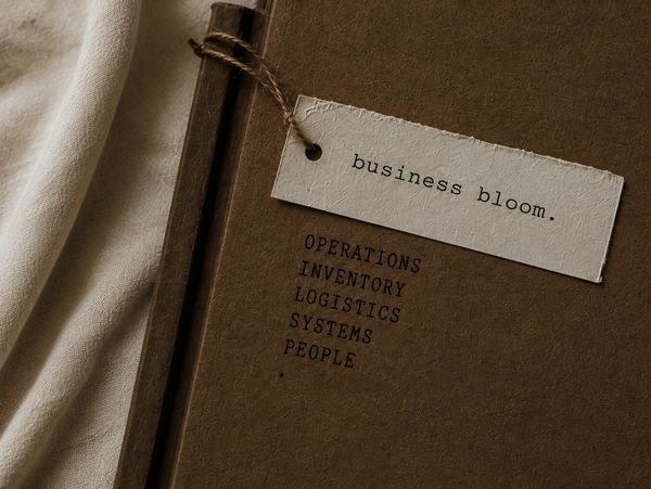 A brown notebook with business-related text and a tag saying 'business bloom.'